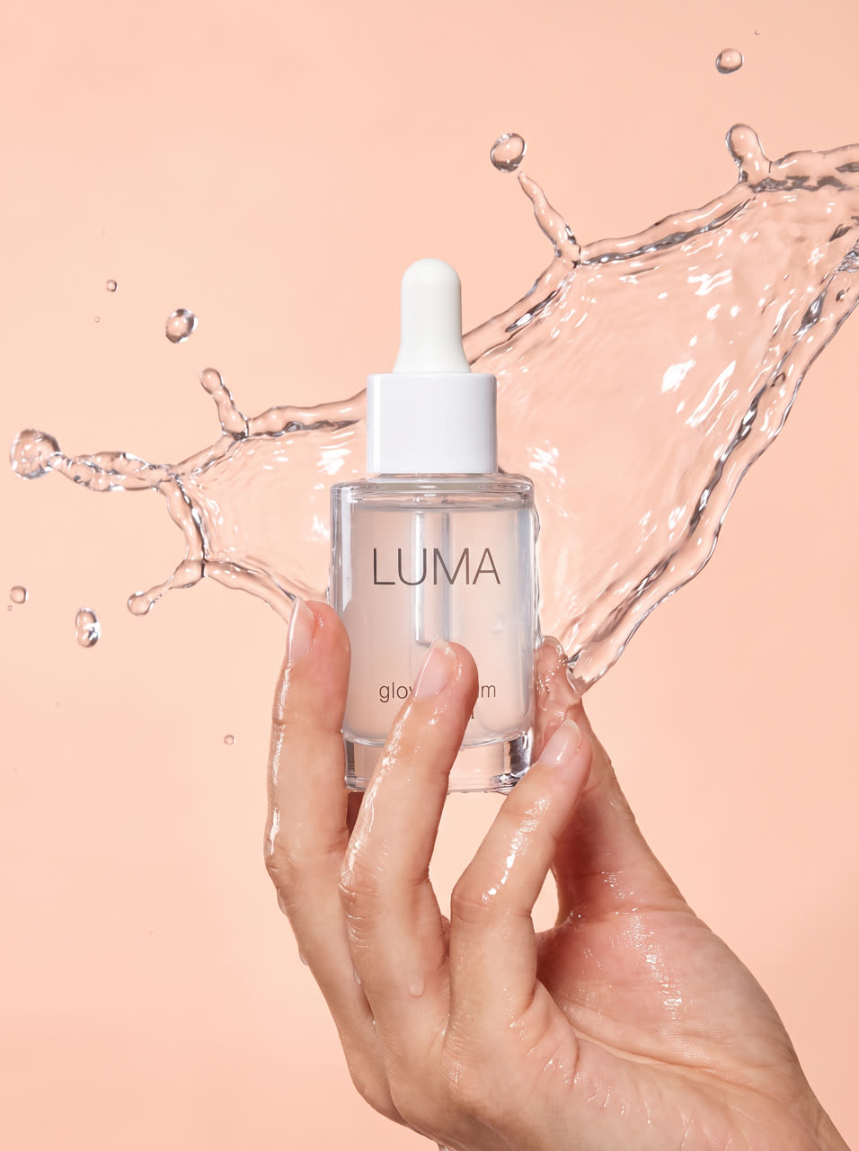 LUMA serum held in a hand with a water splash
